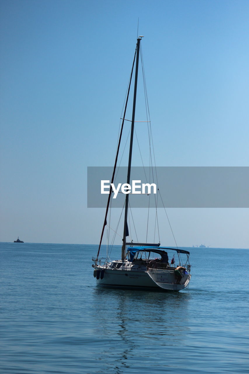 Sailboat sailing on sea against clear sky