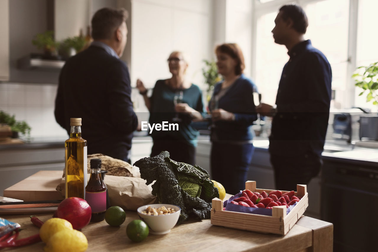 Food on table against friends talking in kitchen