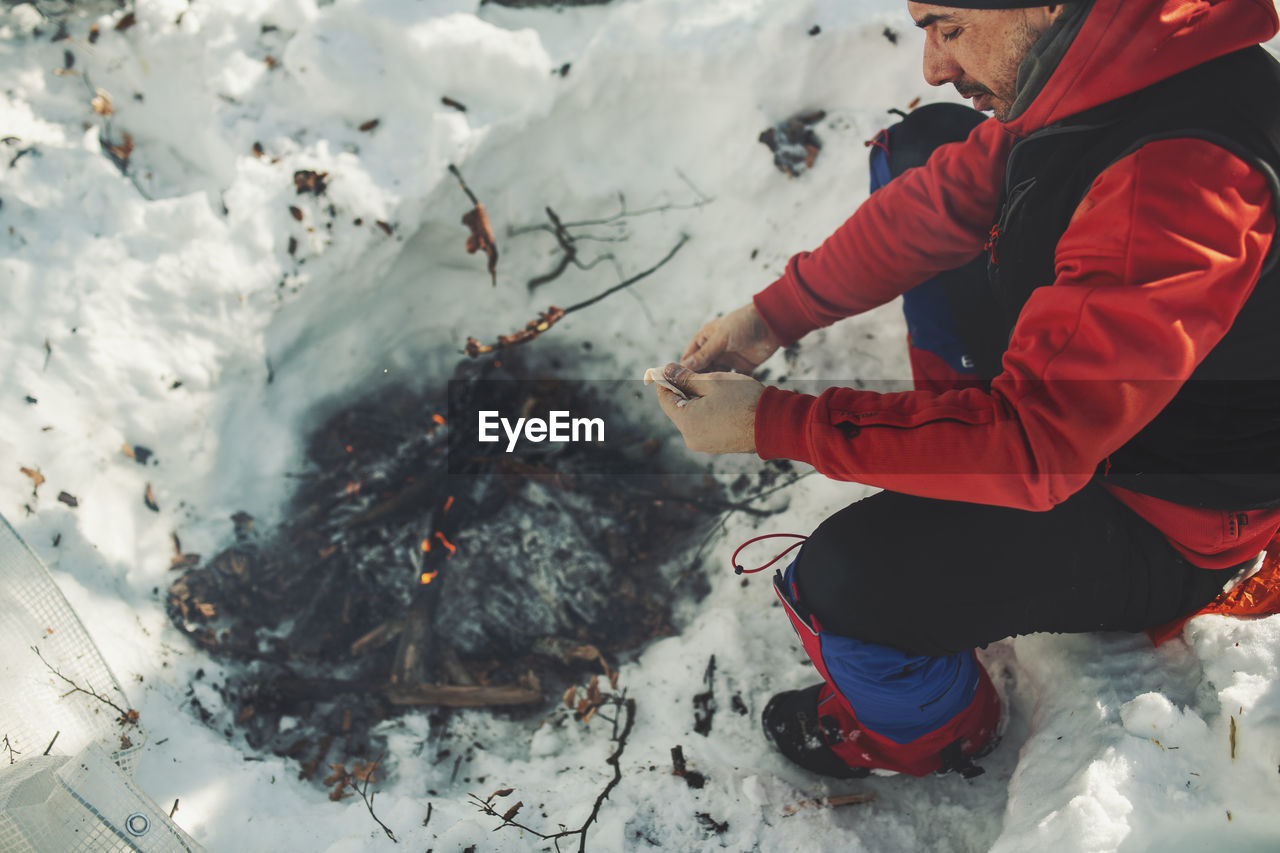 Man preparing meat in bonfire during winter