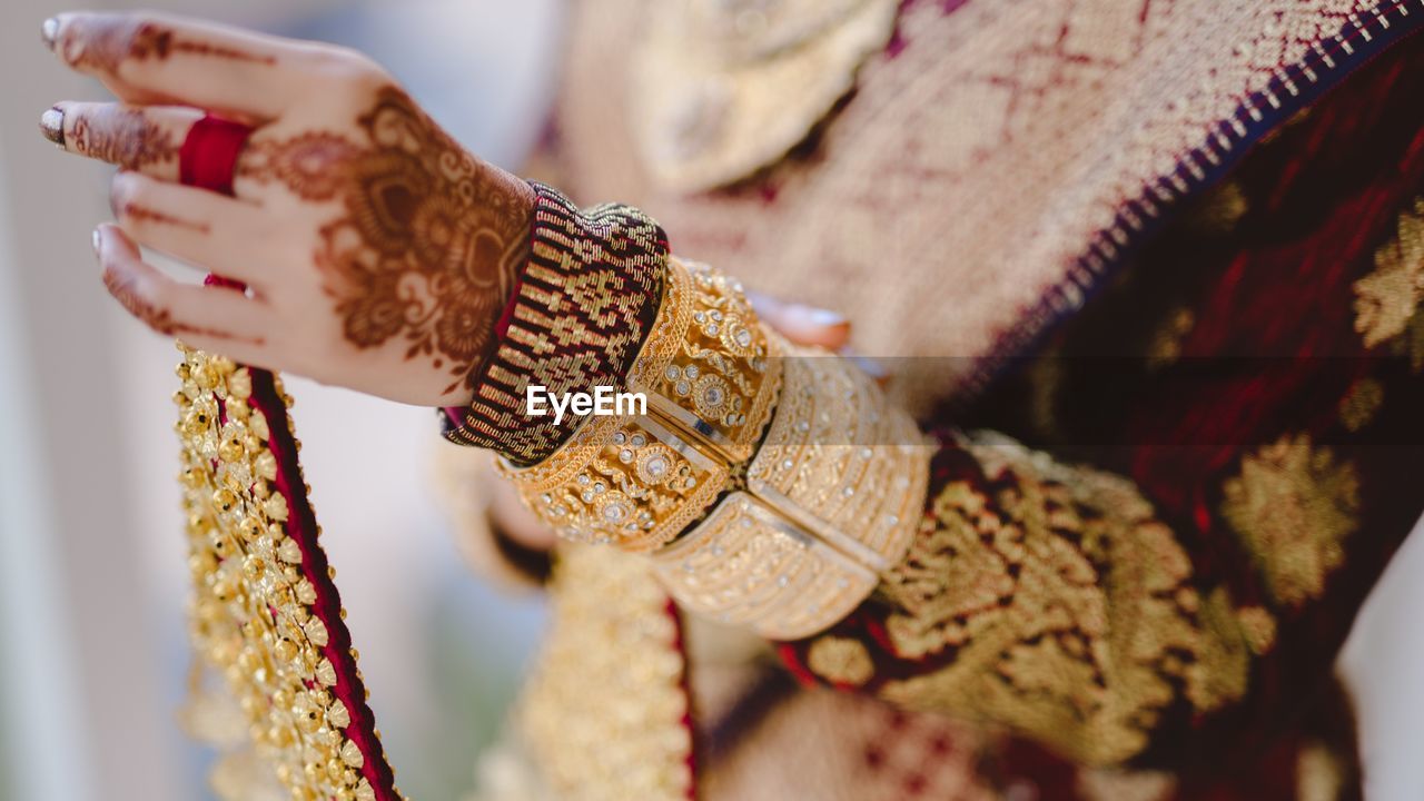 Cropped hand of woman holding gold handkerchief decorations