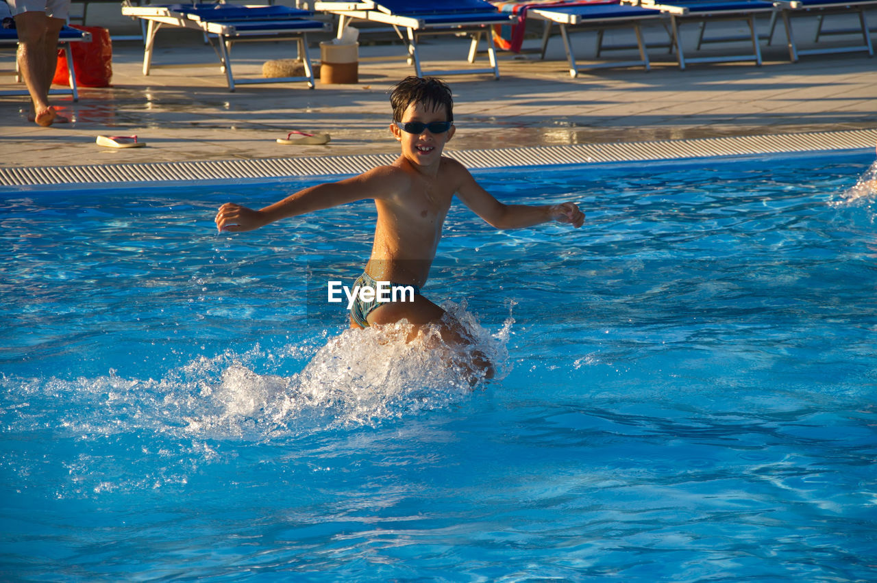 BOY ENJOYING IN SWIMMING POOL