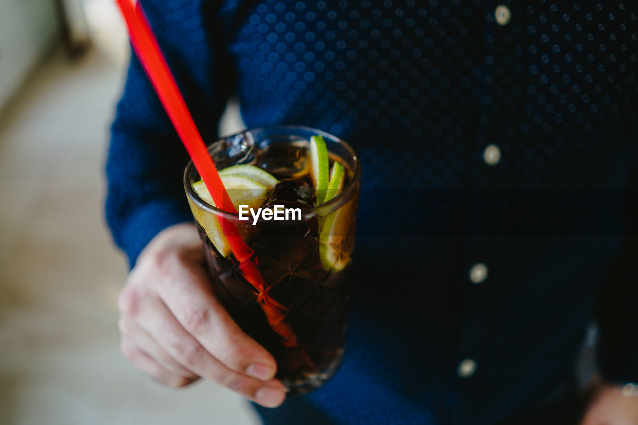 Midsection of man having drink in glass