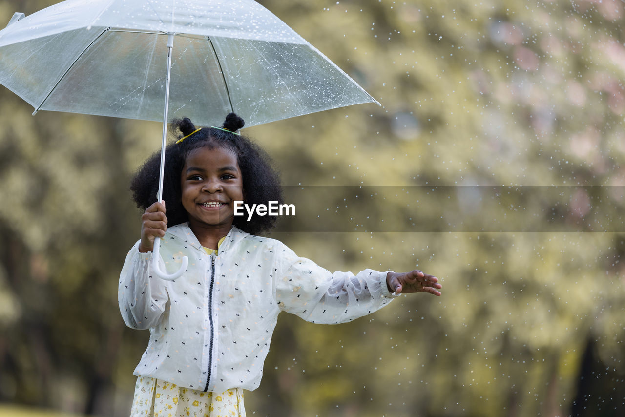 rain, umbrella, wet, protection, happiness, smiling, security, emotion, fashion accessory, childhood, women, nature, one person, cheerful, child, monsoon, rainy season, storm, female, adult, water, positive emotion, drop, cute, portrait, outdoors, enjoyment, environment, holding, lifestyles, fun, joy, parasol, clothing, raindrop, men, motion, standing, coat, front view, smile, city, teeth, summer, day