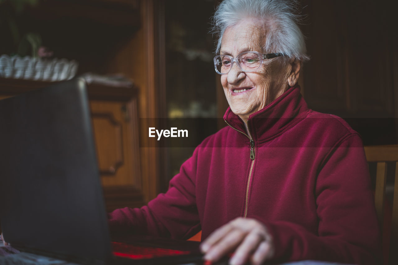 Smiling senior woman using laptop while sitting at home