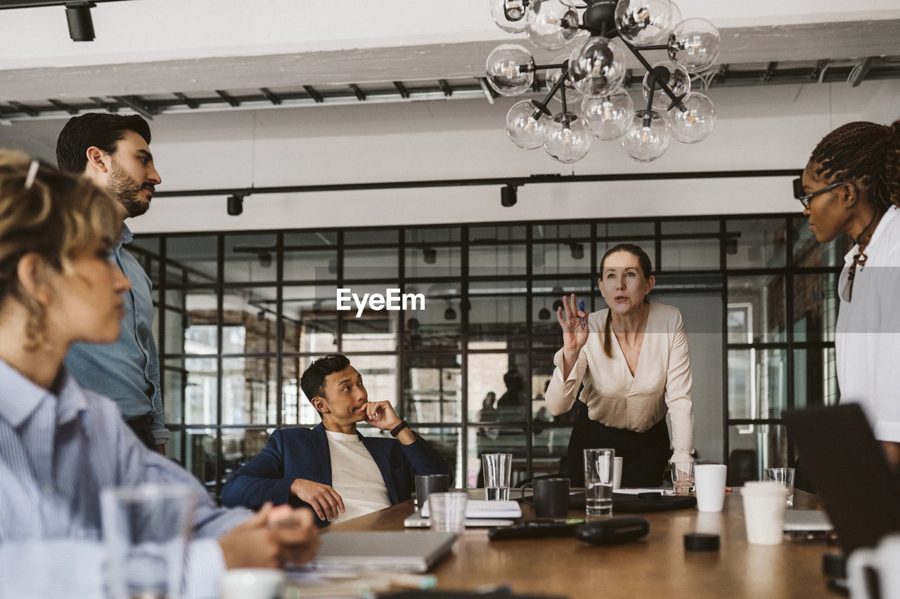 Female professional gesturing while explaining colleagues in board room