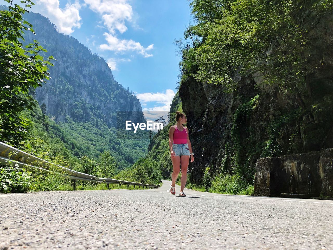 Woman walking on road amidst mountain against sky