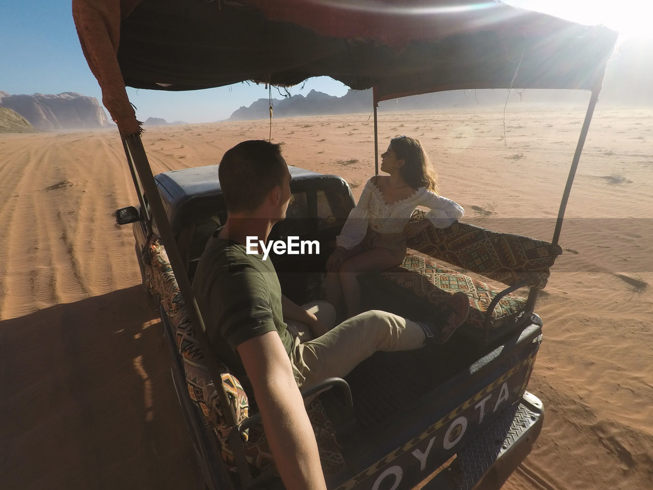 Couple sitting on the back of a car in the desert