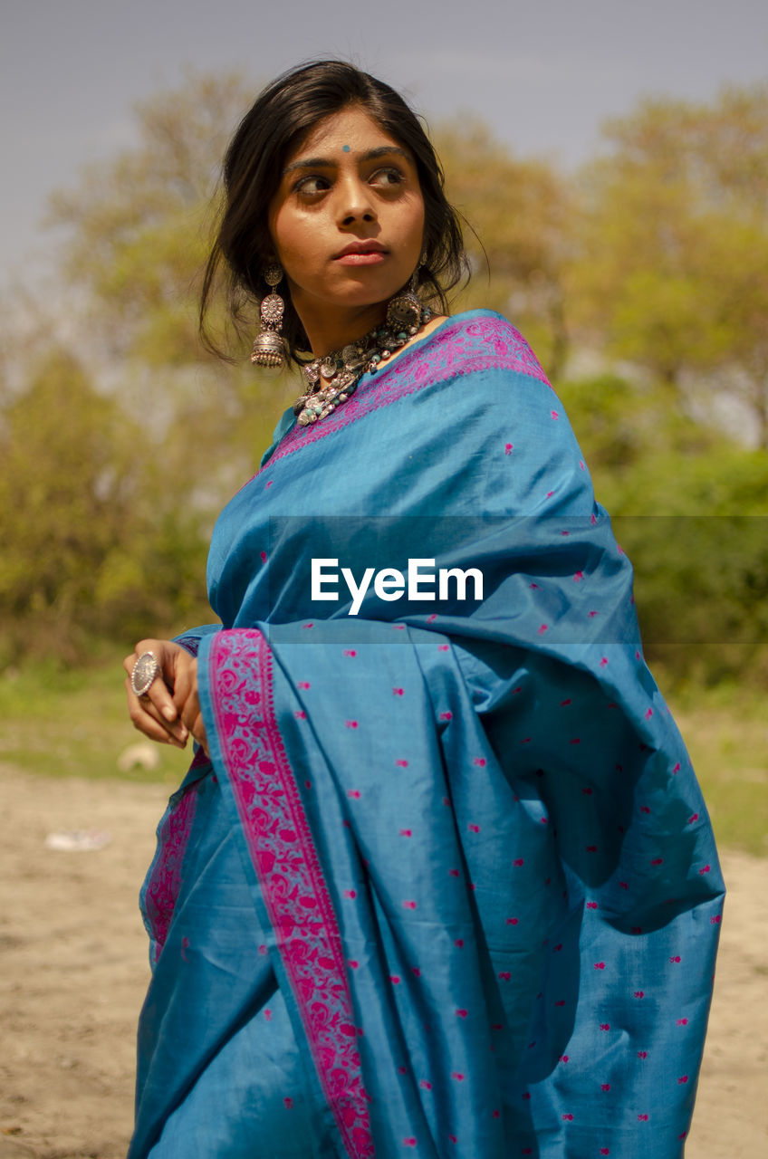 Beautiful woman wearing sari while standing against trees