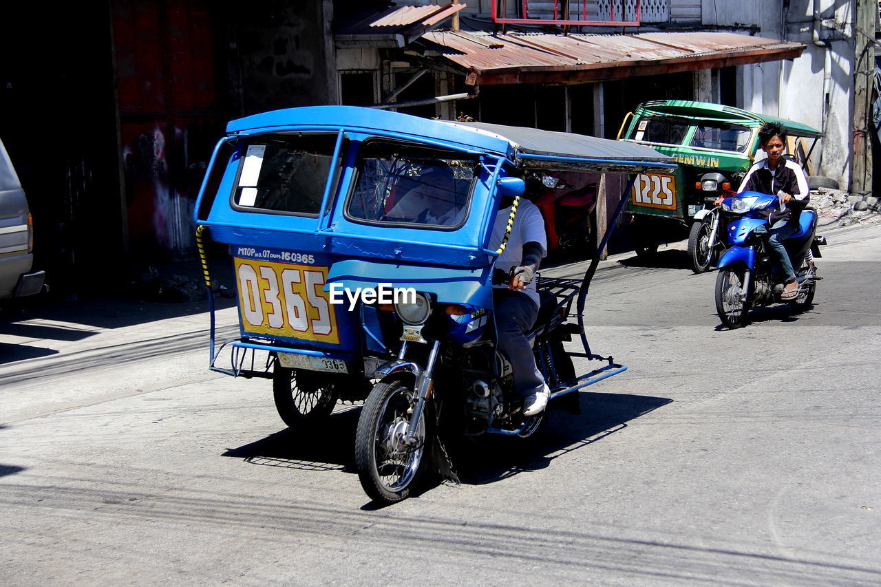 Man driving jinrikisha on city street