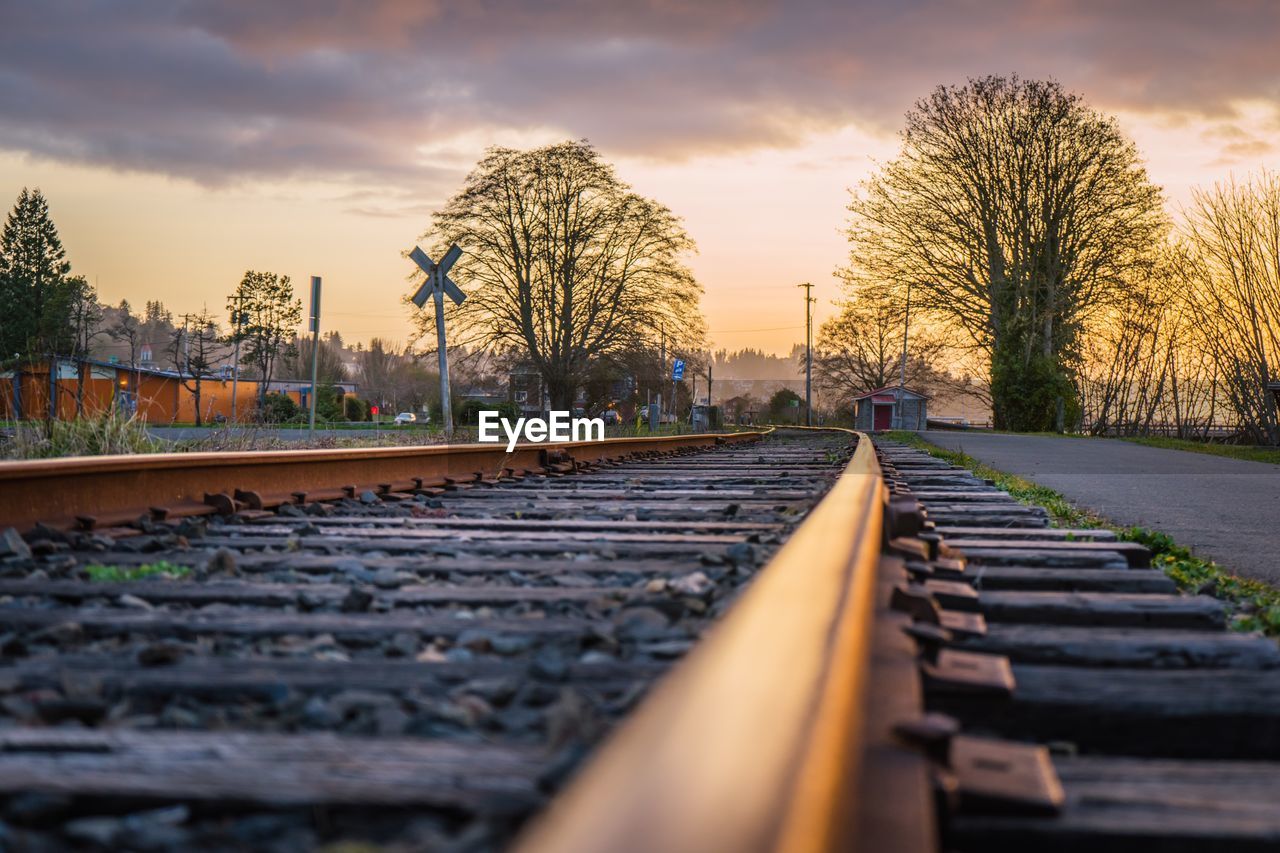 SURFACE LEVEL OF RAILROAD TRACKS AGAINST SKY AT SUNSET