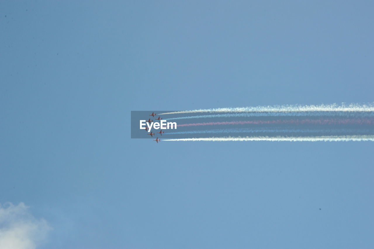 Low angle view of airshow against clear blue sky red arrows