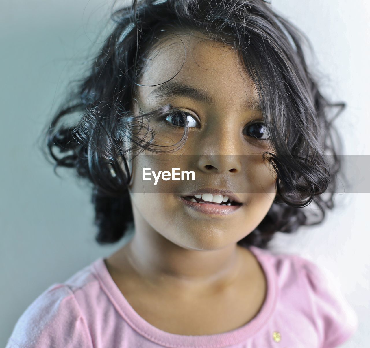 Close-up portrait of smiling girl against wall