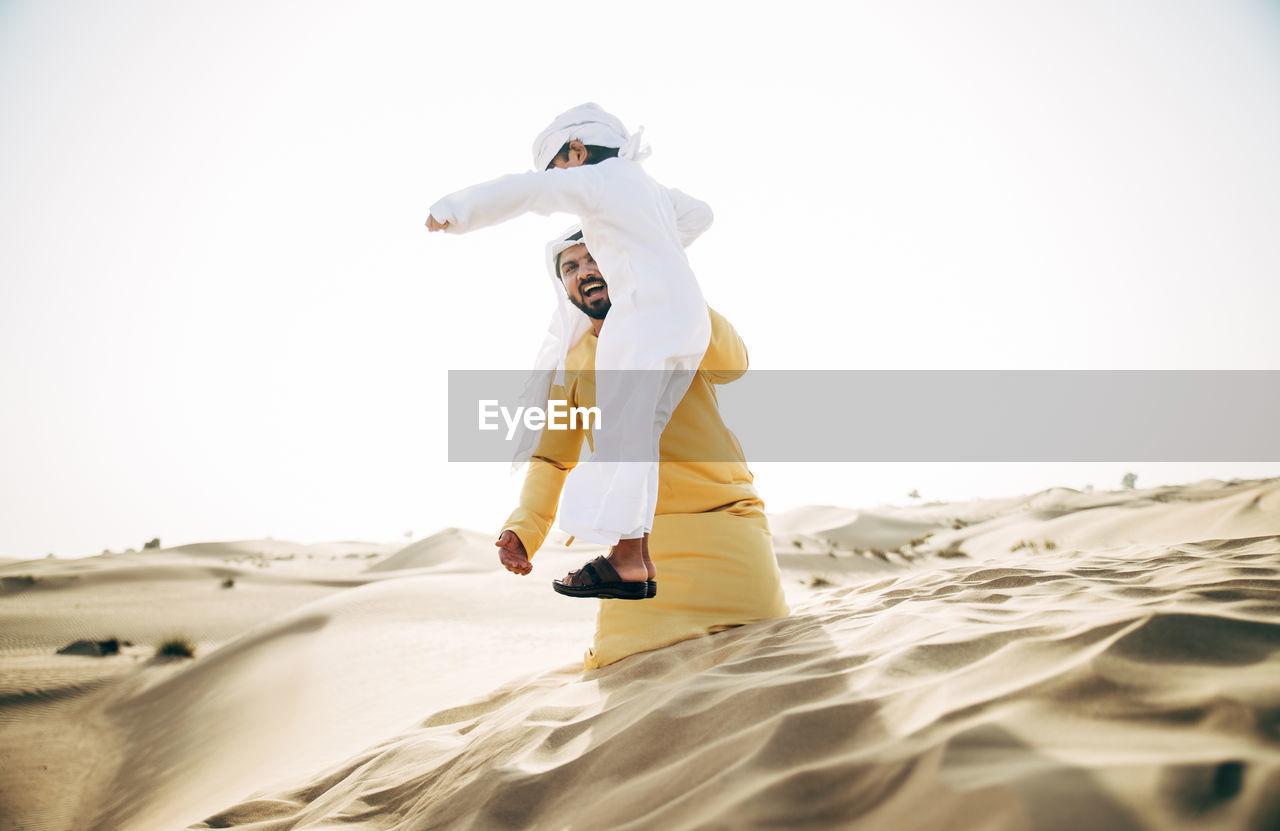 FULL LENGTH OF MAN STANDING ON SAND DUNE