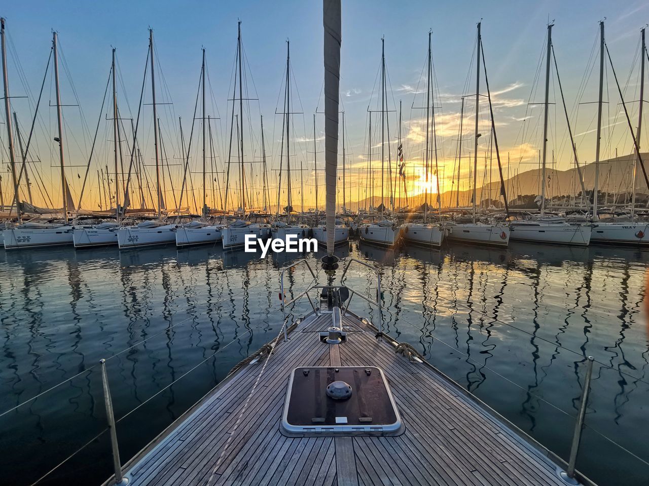 SAILBOATS MOORED AT HARBOR AGAINST SKY