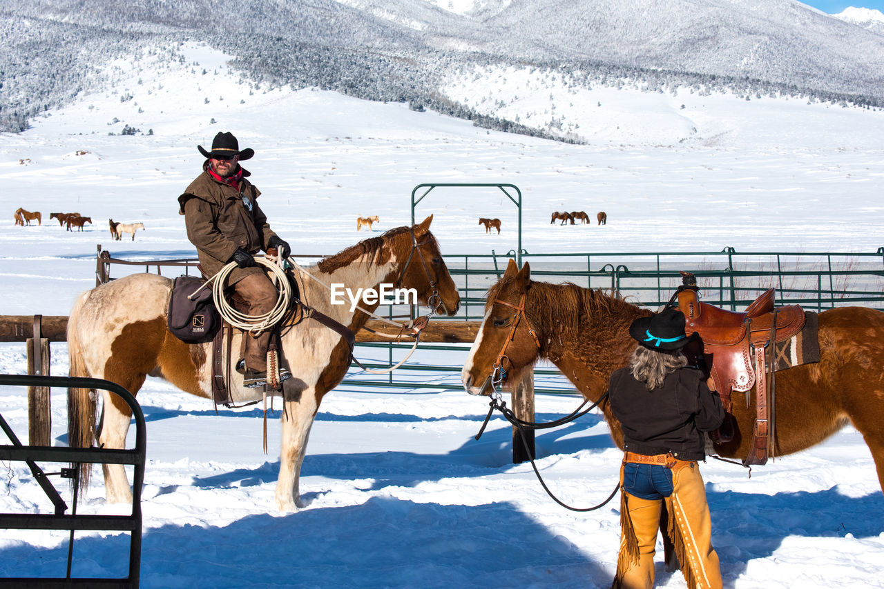 People with horse on snow covered land at ranch