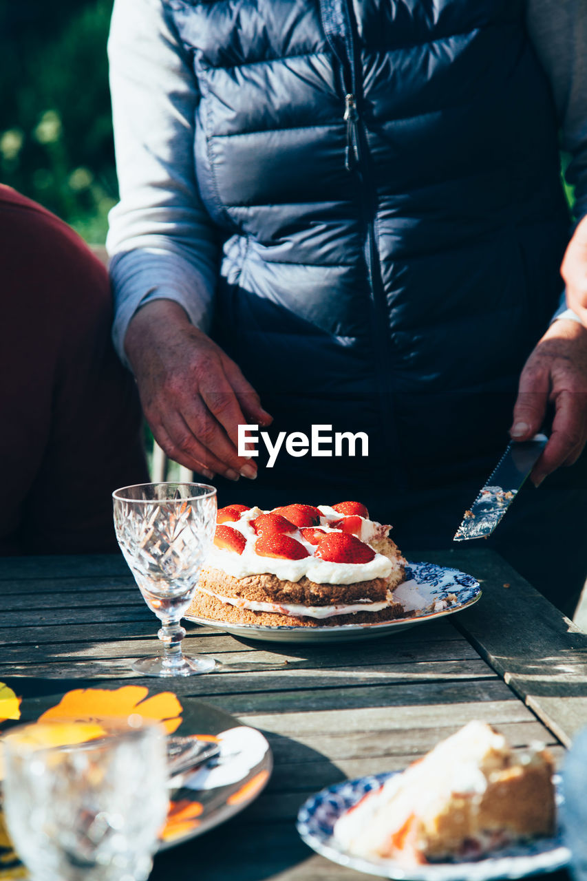 Midsection of woman standing by cake in back yard