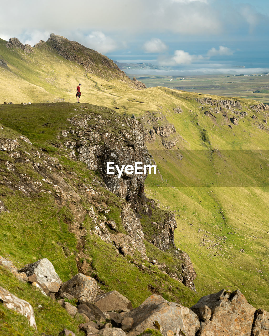 Adult man looking at the storr - rock formations in trotternish landslip, isle of skye, scotland