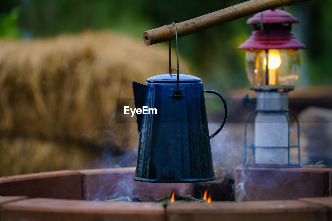 lighting, heat, burning, nature, household equipment, food and drink, kettle, kitchen utensil, fire, no people, food, blue, smoke, focus on foreground, wood, lighting equipment, steam, cooking pan, outdoors, day, flame, lantern, hanging, plant