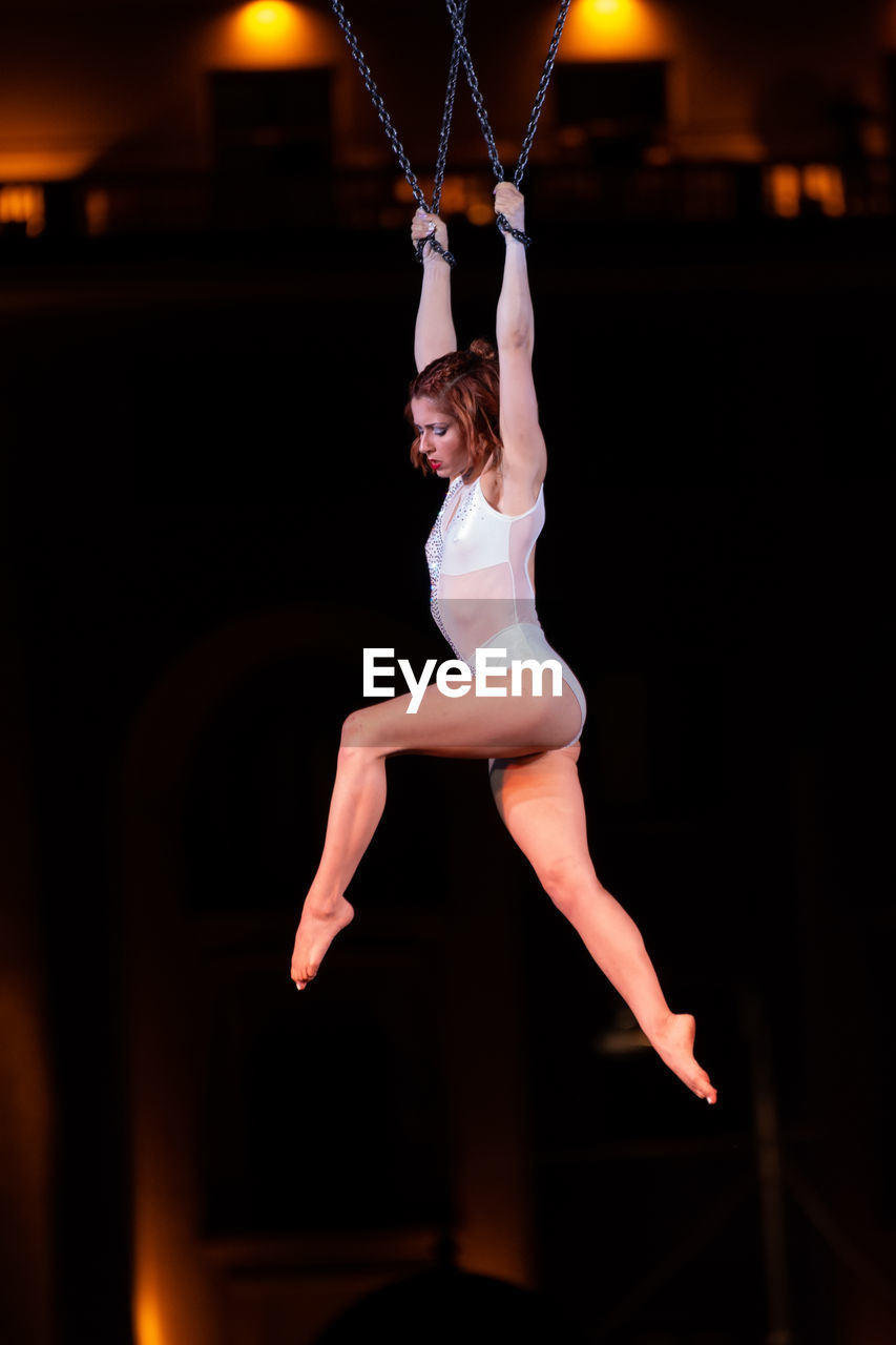 MIDSECTION OF WOMAN WITH ARMS RAISED WHILE STANDING ON FLOOR