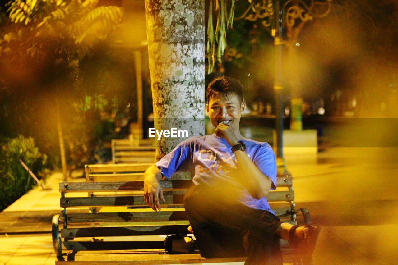 Portrait of man sitting on bench at night