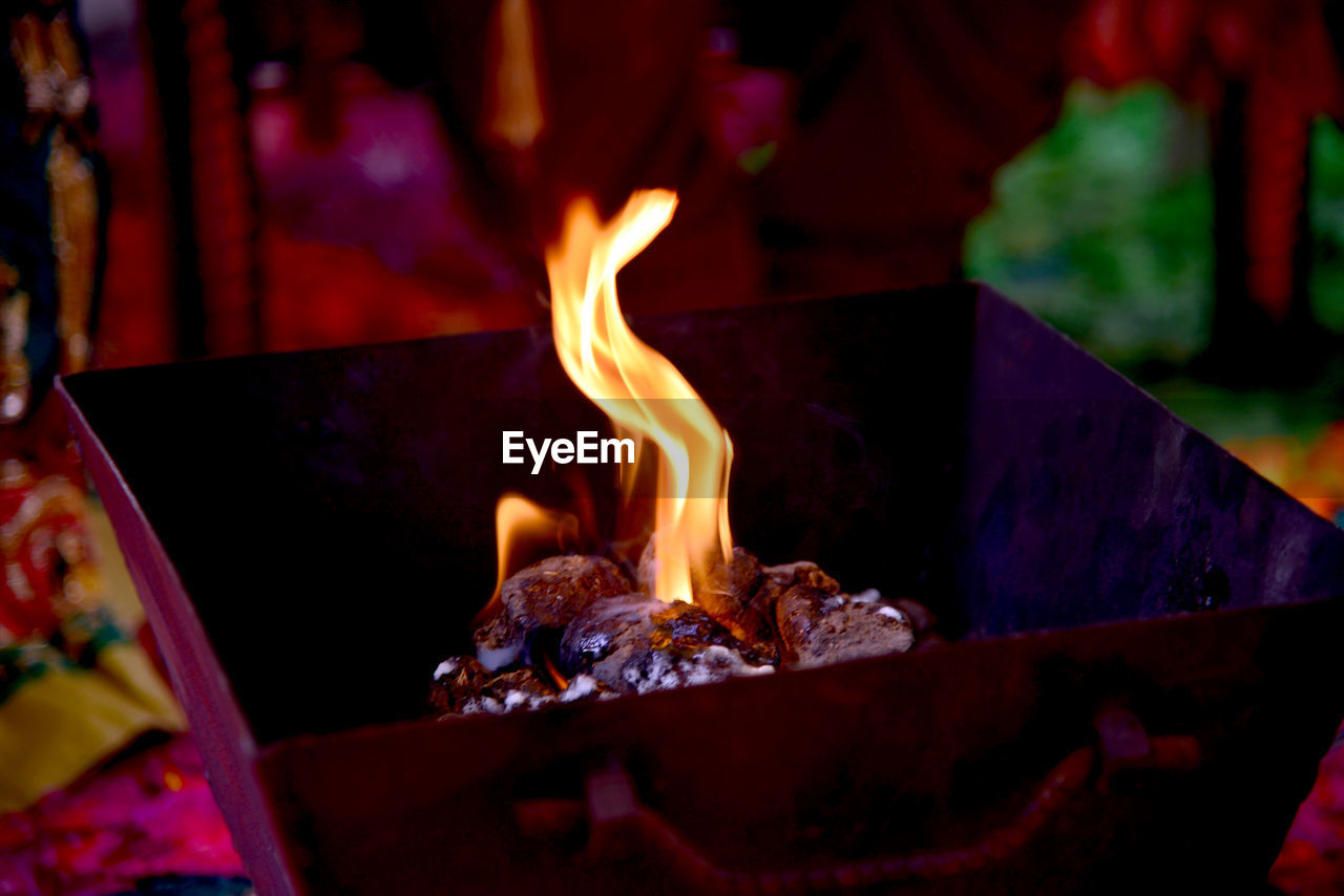 CLOSE-UP OF BURNING CANDLES ON WOODEN TABLE