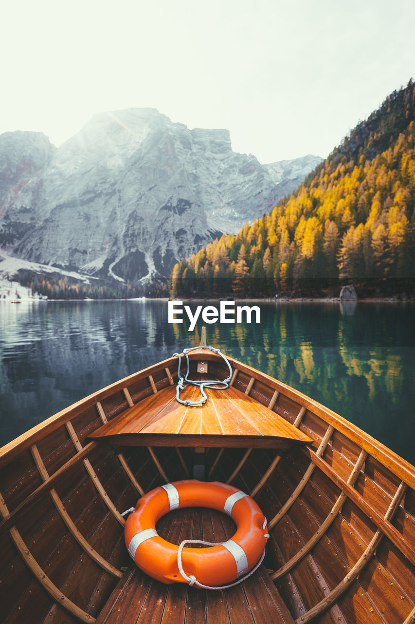 Wooden boat moored in lake by mountains