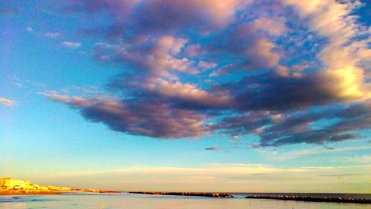 SCENIC VIEW OF DRAMATIC SKY OVER SEA AGAINST CLOUDY BLUE BACKGROUND