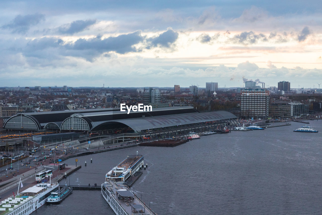 HIGH ANGLE VIEW OF RIVER AMIDST BUILDINGS IN CITY AGAINST SKY