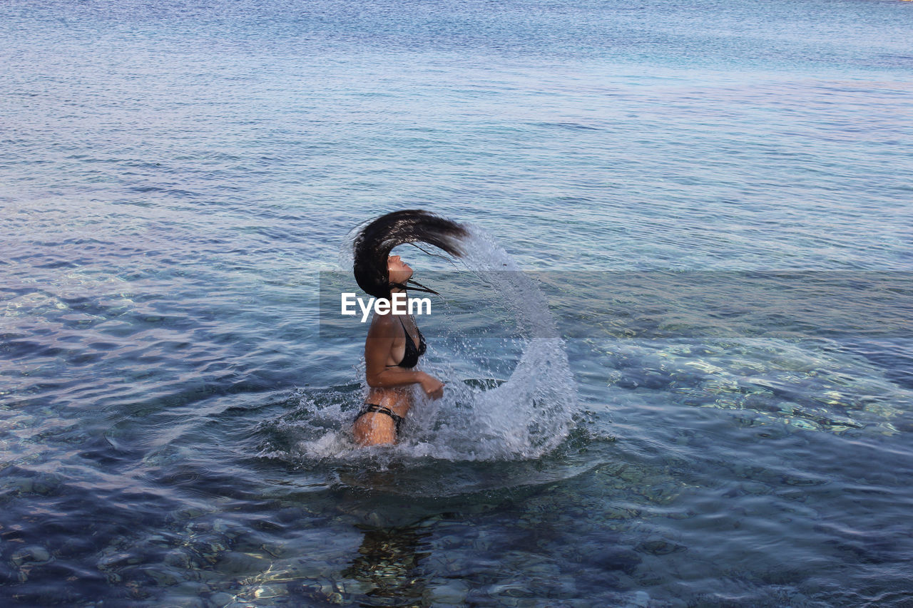 full length of shirtless man jumping in sea