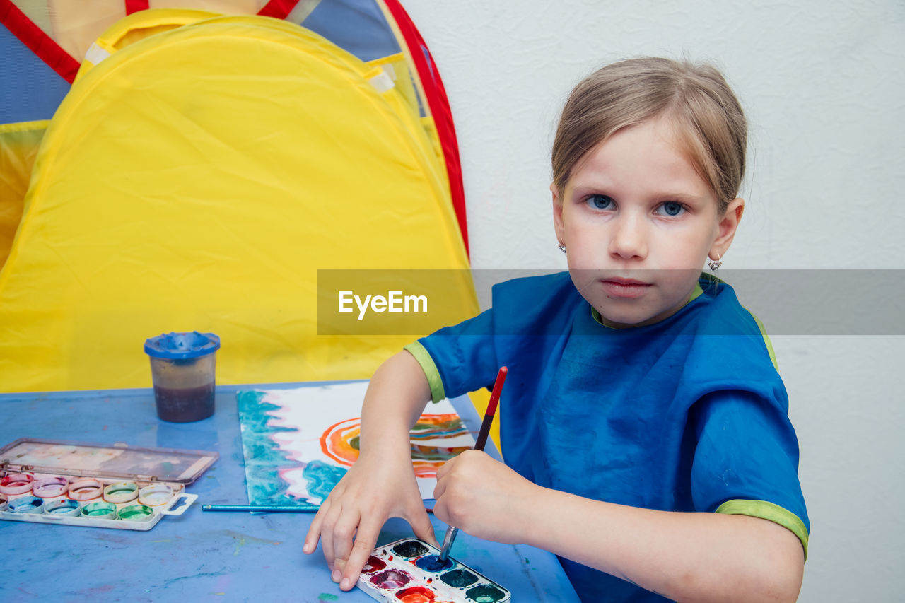 Portrait of girl painting by tent