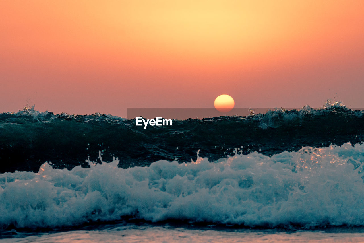 Close-up of sea wave against sky during sunset