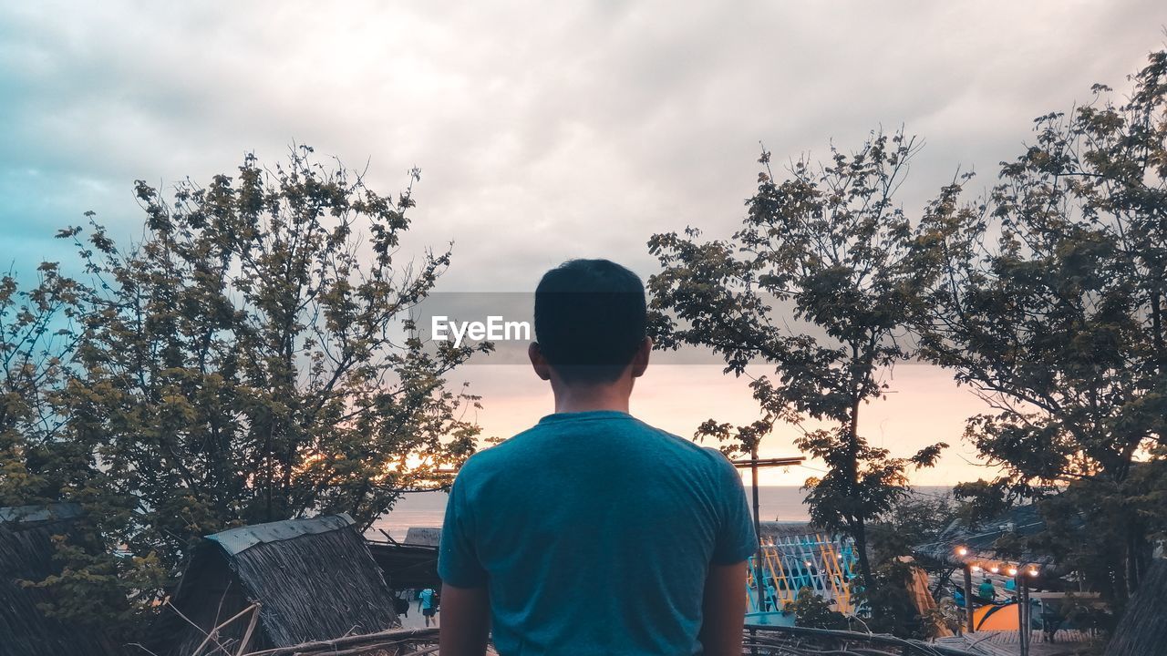 Rear view of man against sky and trees