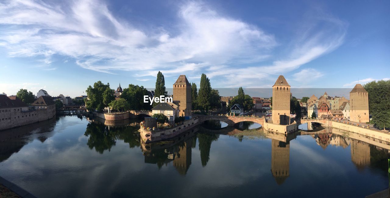 Bridge over river by buildings against sky