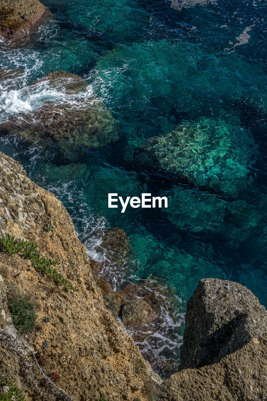 CLOSE-UP OF ROCKS BY SEA