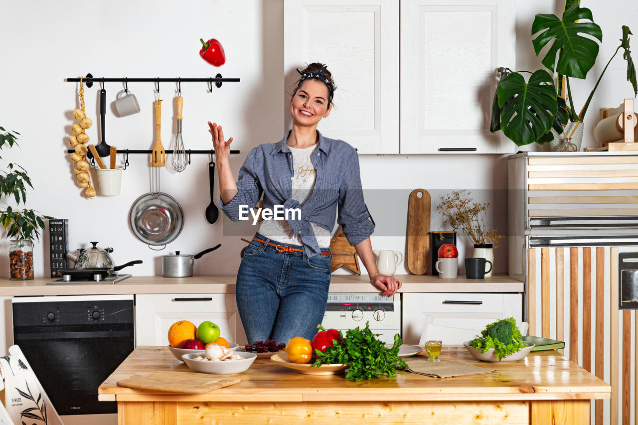 Young and beautiful housewife woman cooking in a white kitchen