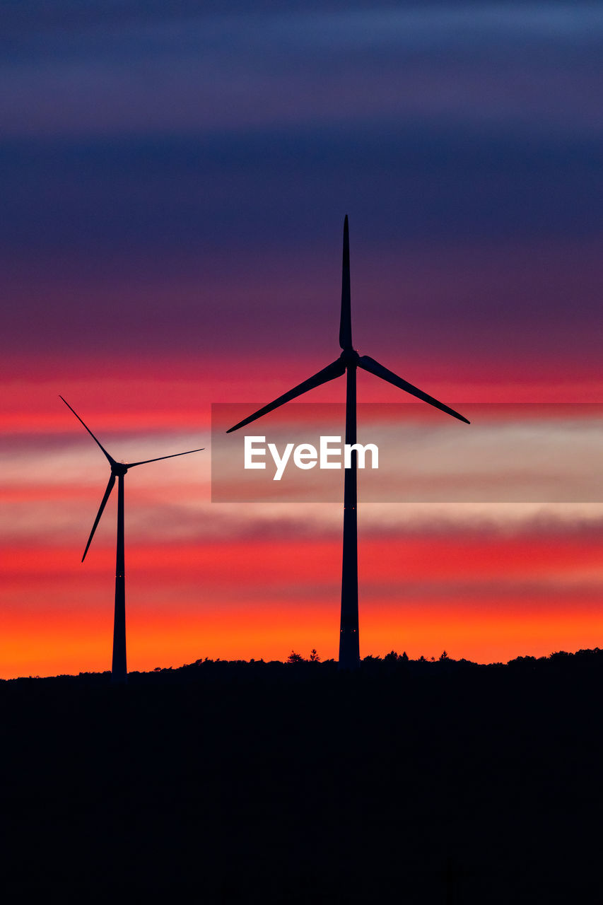 SILHOUETTE WIND TURBINES ON LANDSCAPE AGAINST ROMANTIC SKY