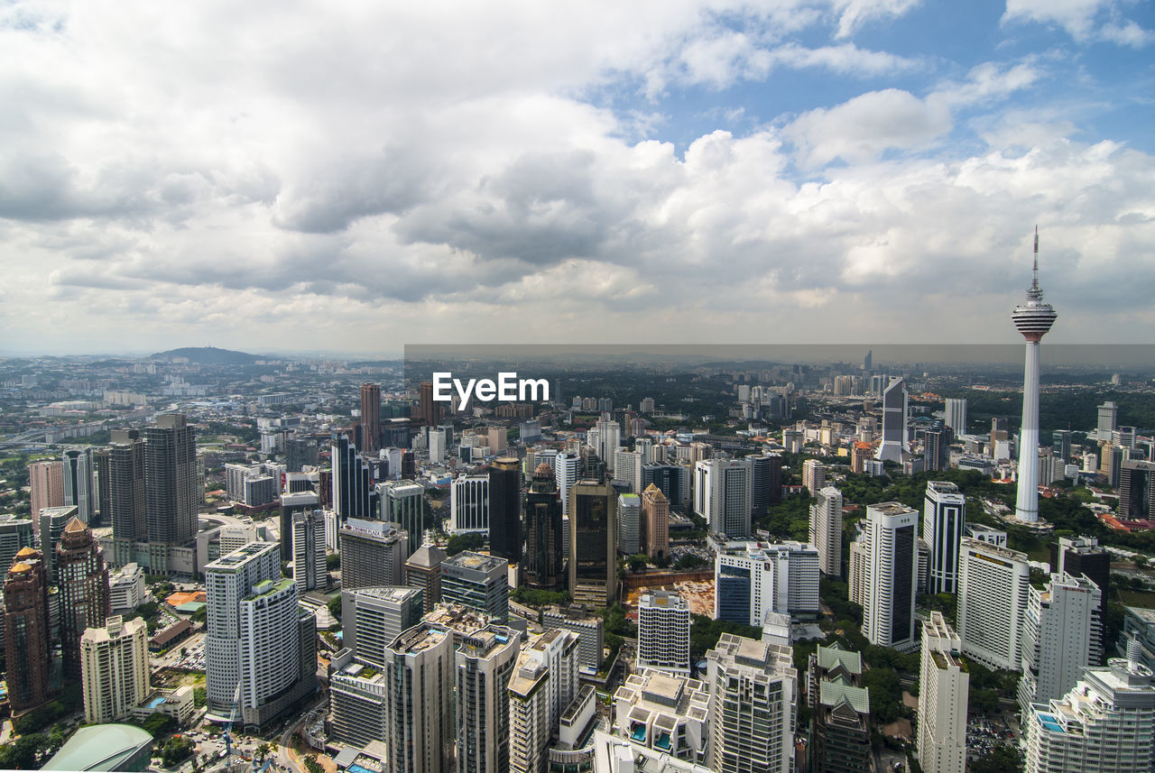 Aerial view of buildings in city against cloudy sky
