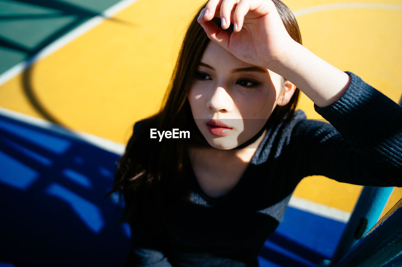 High angle view of young woman looking away while standing outdoors