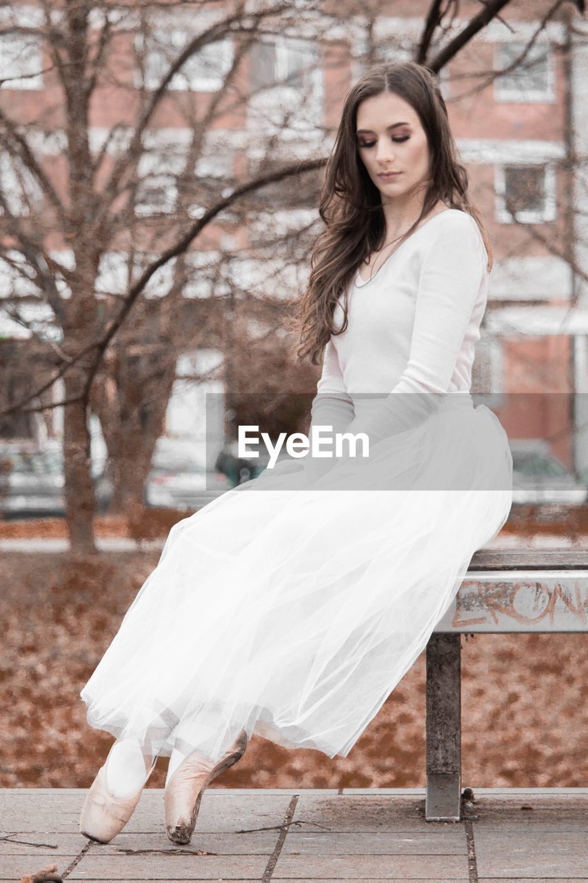 Side view of young woman sitting on bench