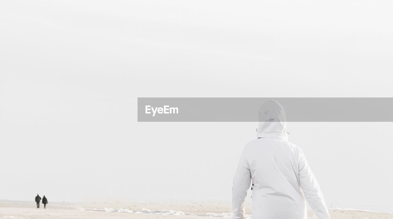 Rear view of man walking on snow covered landscape