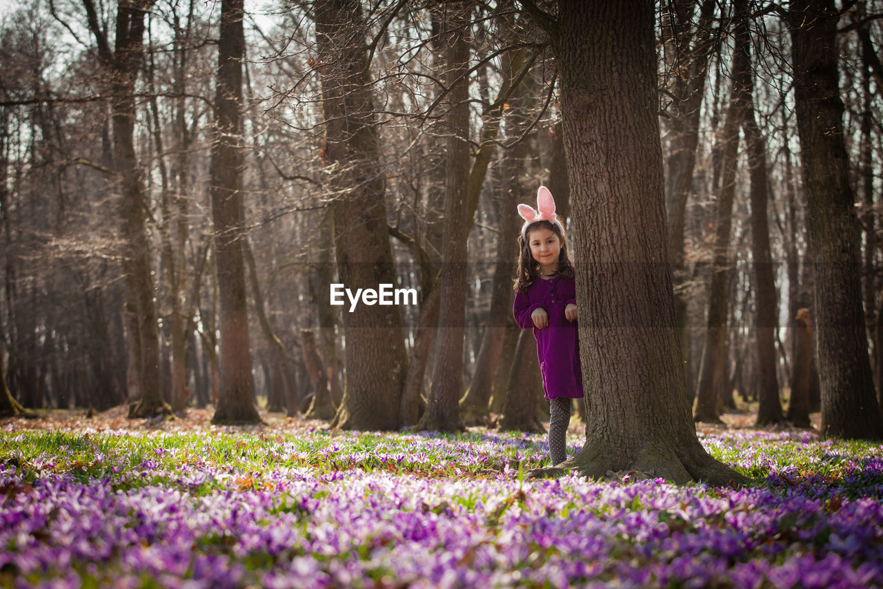 PORTRAIT OF WOMAN WITH PURPLE FLOWERS IN GARDEN