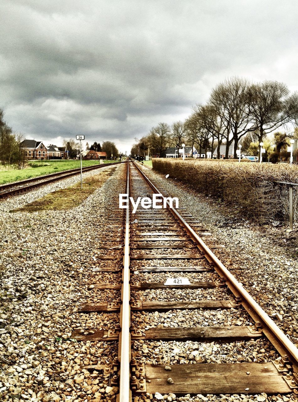 Railroad tracks against cloudy sky