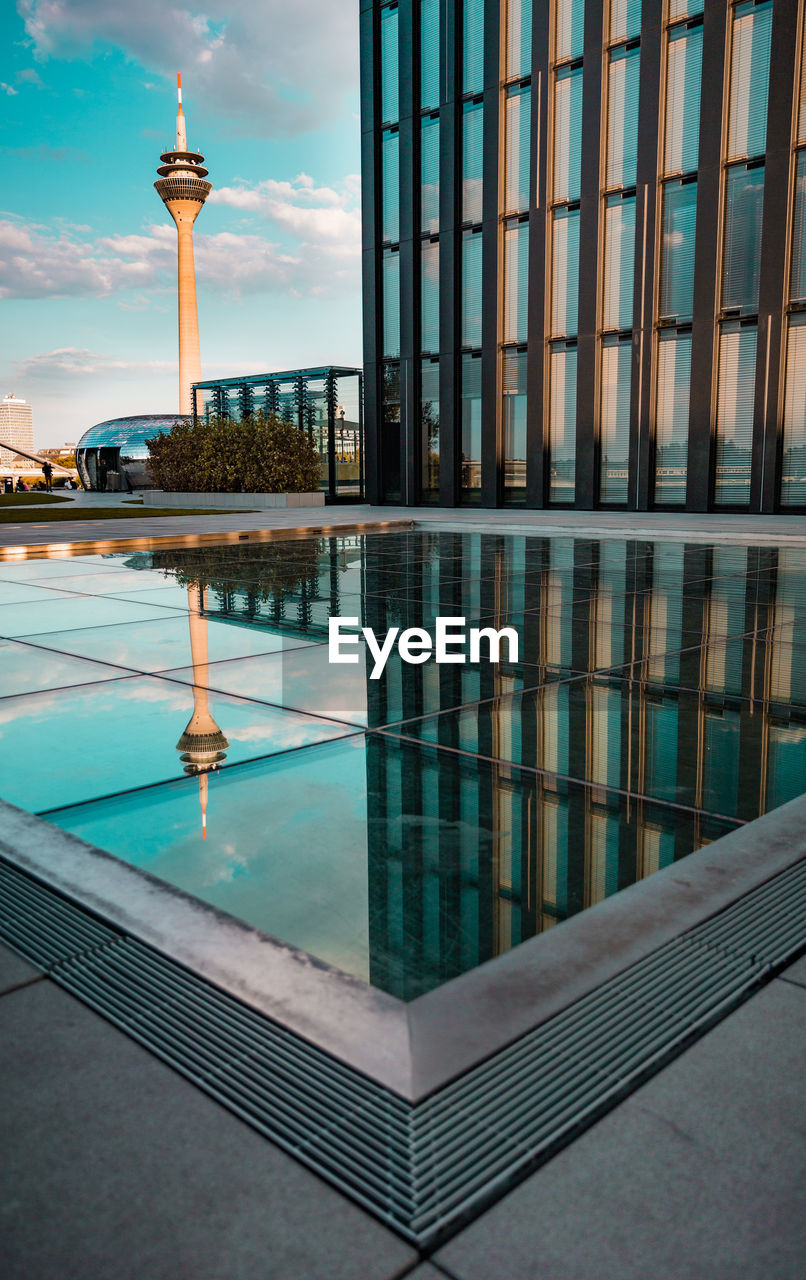 REFLECTION OF MODERN BUILDING IN WATER WITH SKYSCRAPERS IN BACKGROUND