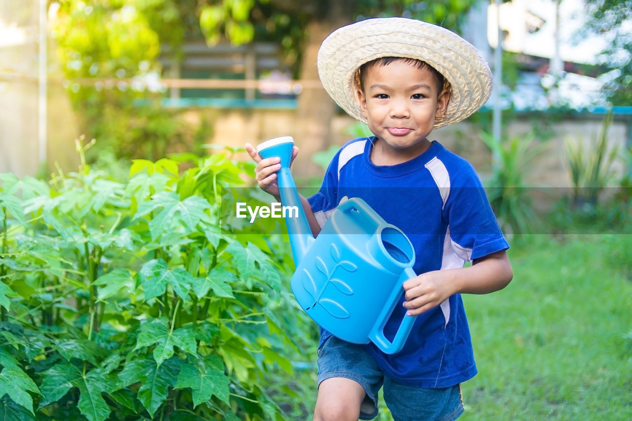 Portrait of boy holding watering can outdoors