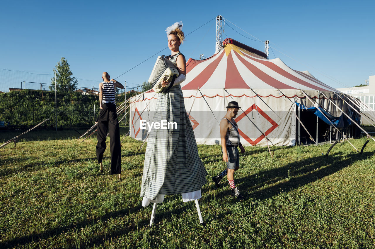 Circus artists performing while walking on meadow