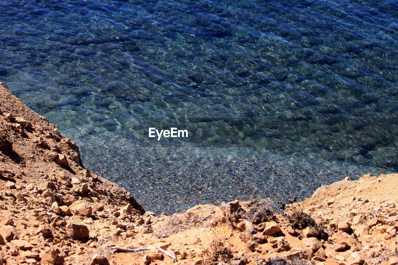 soil, sea, water, nature, beauty in nature, day, high angle view, no people, land, geology, tranquility, scenics - nature, rock, tranquil scene, natural environment, outdoors, beach, blue, sunlight, shore, non-urban scene, coast, mountain, idyllic, sand