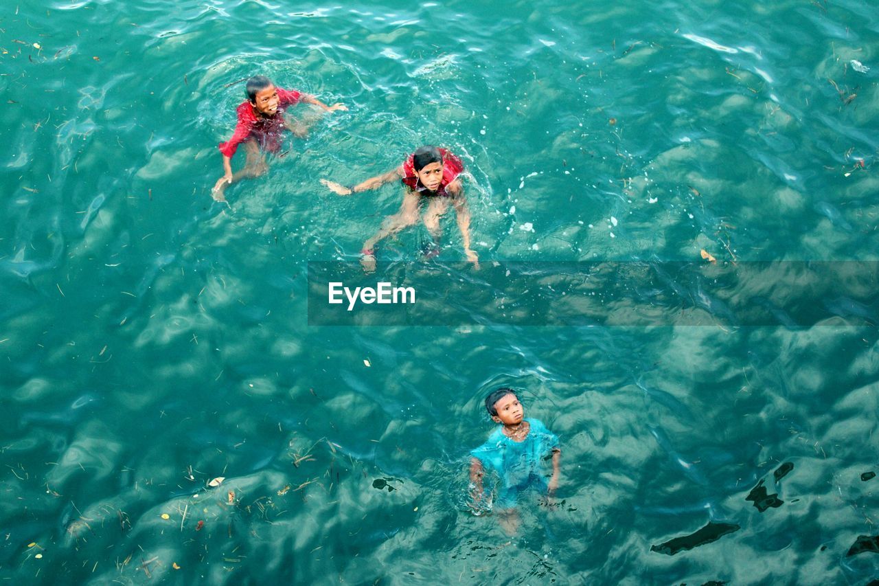 HIGH ANGLE VIEW OF FRIENDS SWIMMING IN SEA