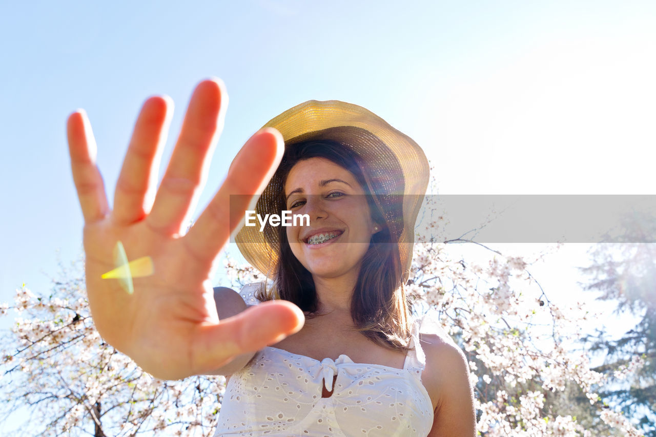 low angle view of young woman standing against clear sky