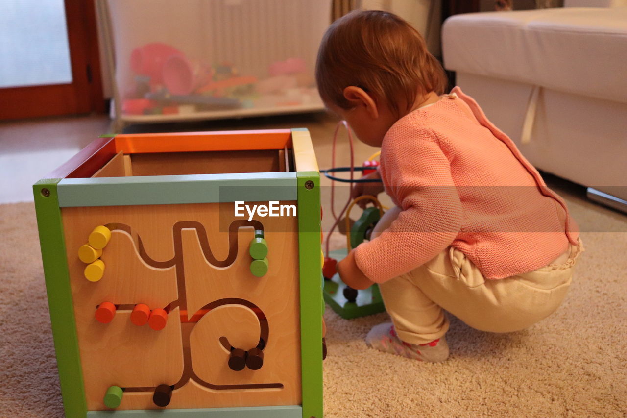 Girl playing with toy on rug at home 