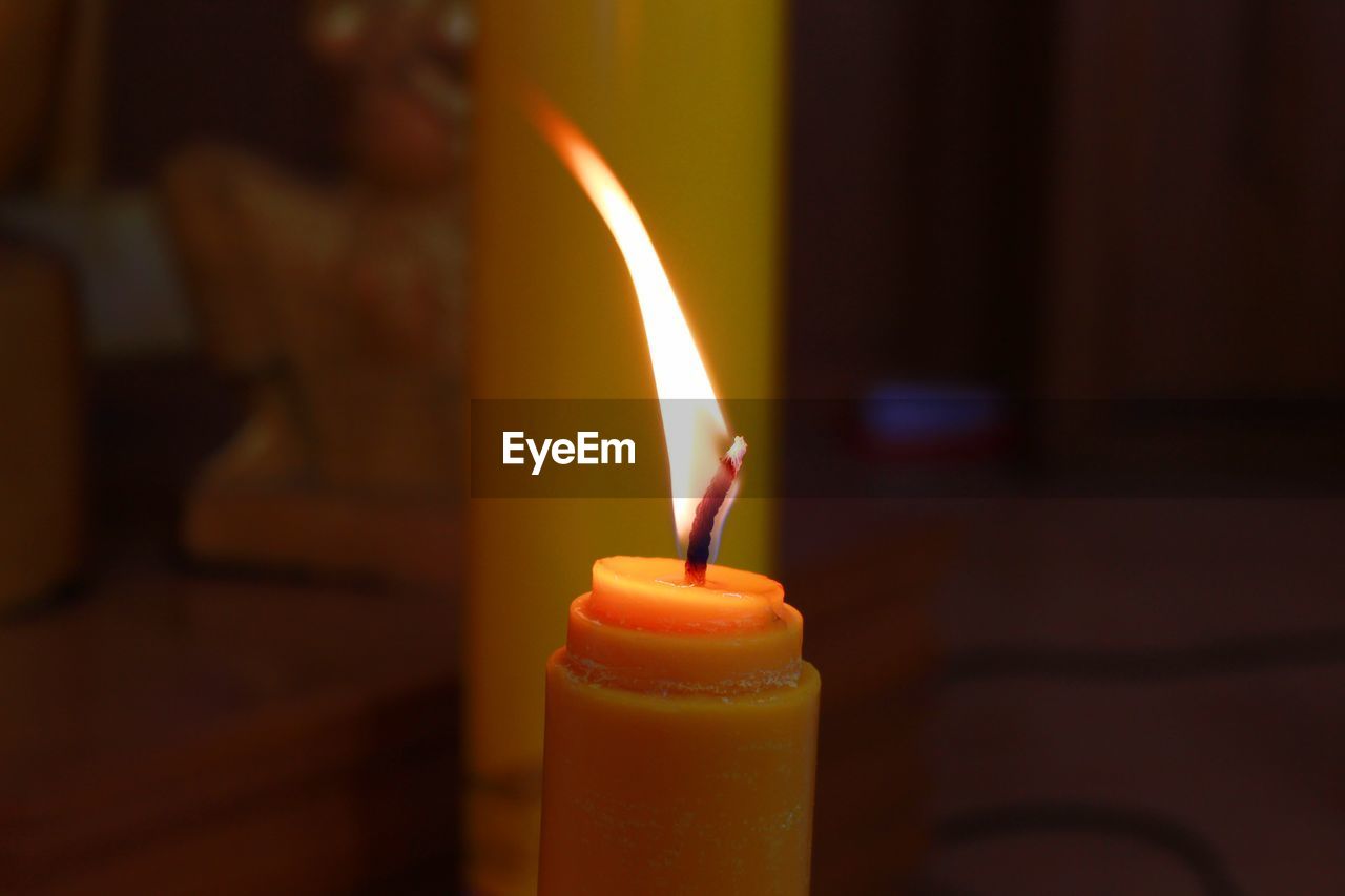 Close-up of burning candle in darkroom